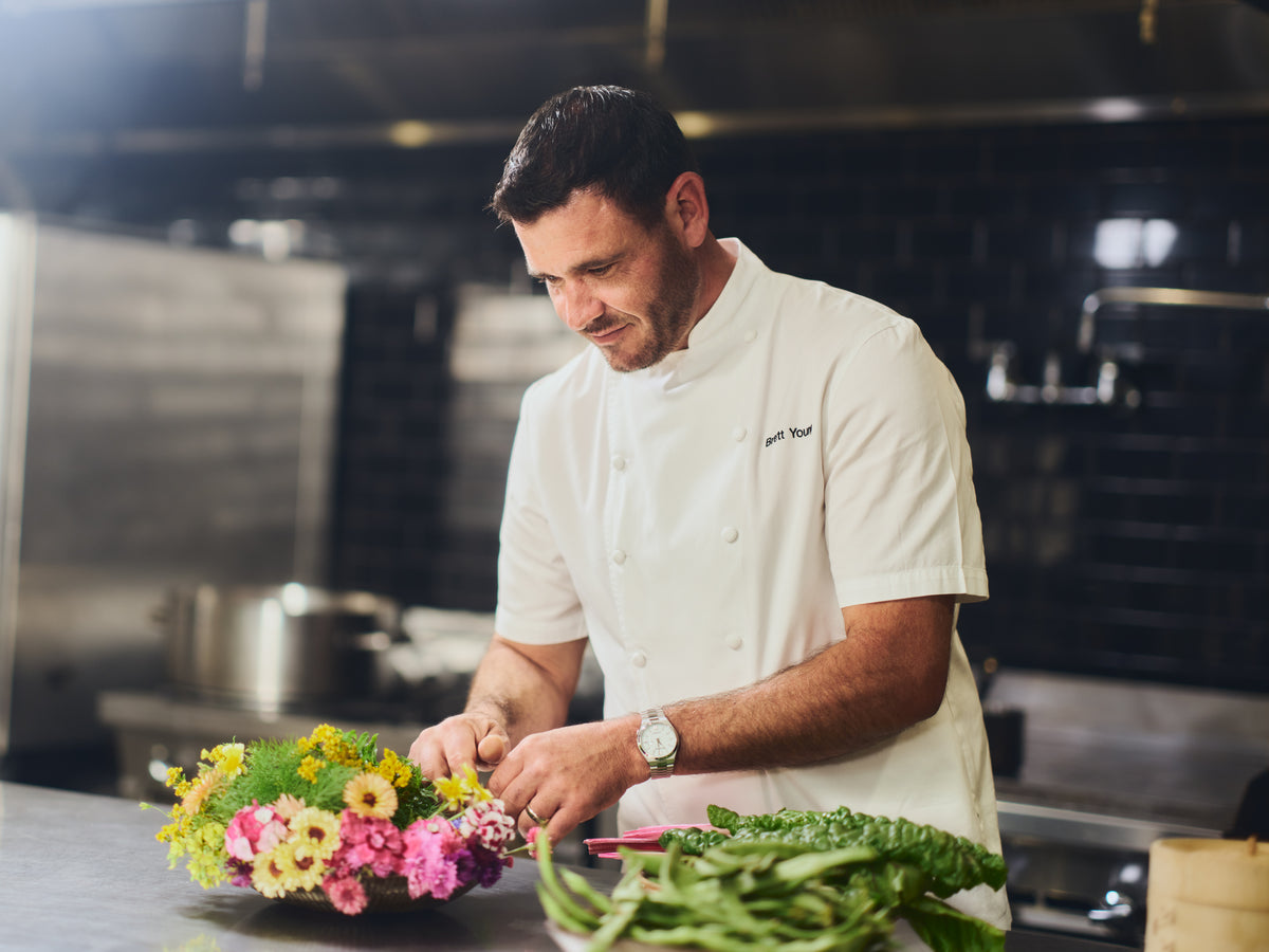 image of our chef Brett Young in the kitchen with vegetables and flowers 
