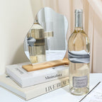 Bottle of white wine on a table with decorative items including a mirror, books, and a vase.