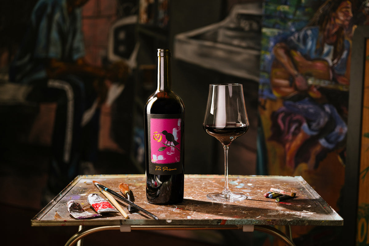 image of a wine bottle on a table with a wine glass and paint brushes 
