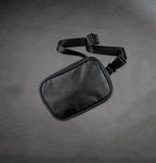 Leather belt bag with The Prisoner logo on the front on a gray background