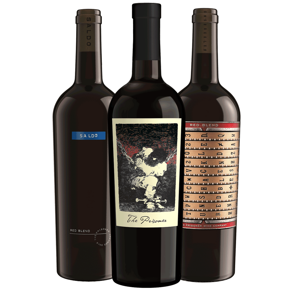 Three dark glass wine bottles grouped together on a white background. The center bottle is The Prisoner Red Blend'; the left bottle is dark brown with a blue 'SALDO' label; the right bottle is also dark brown with a beige and red patterned Unshackled Red Blend label.