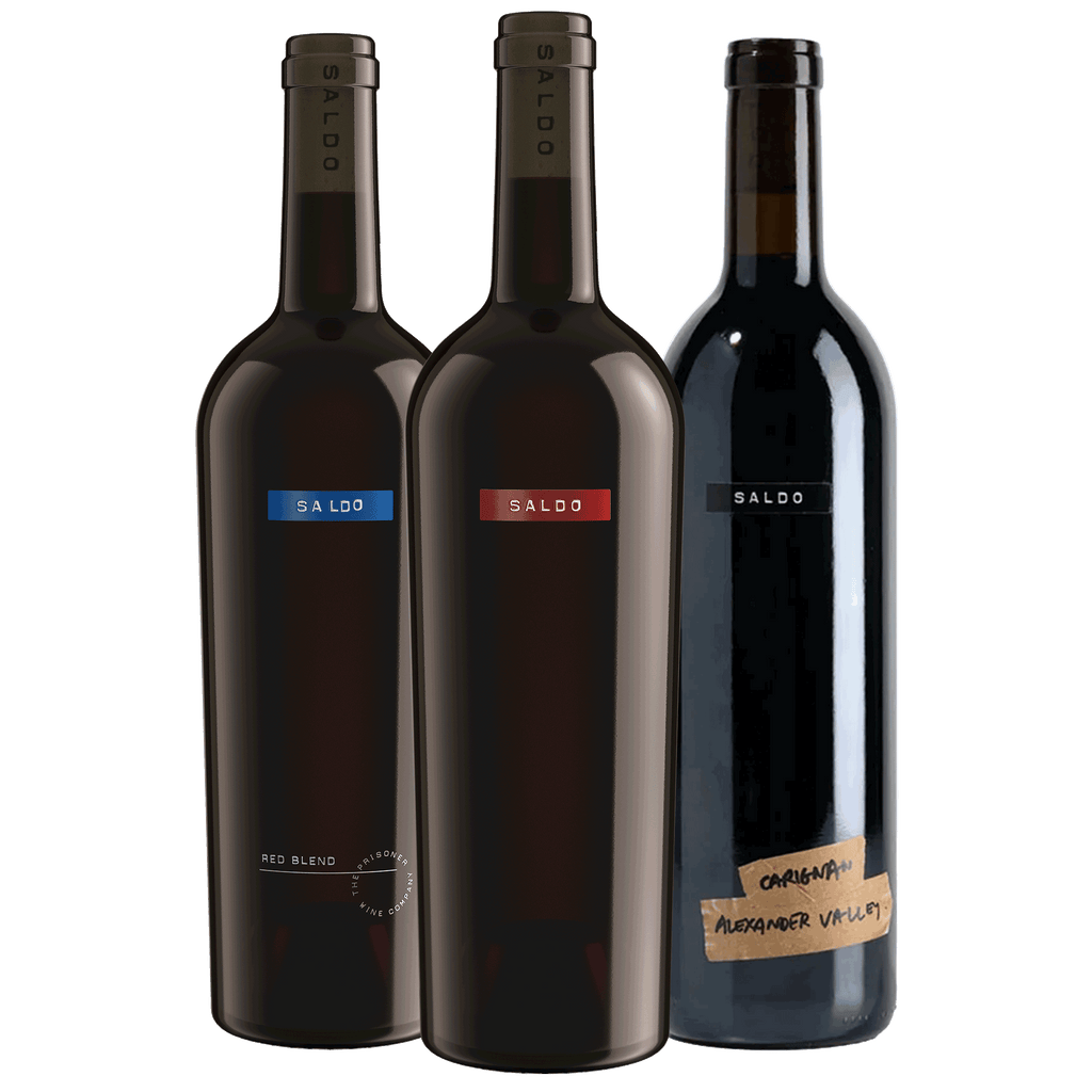 Three Saldo wine bottles on a white background: the Red Blend bottle with a blue label accent, the Zinfandel bottle with a red label accent, and the Carignan bottle with a brown tape label.