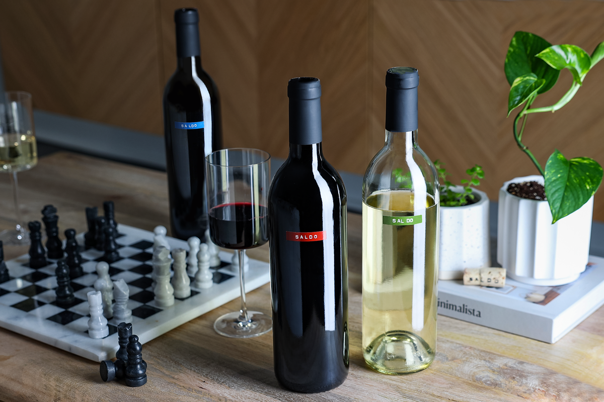 SALDO bottles of wine on a table with chess board and plant pot and glass of wine