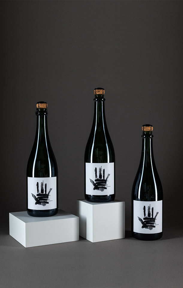 three bottles of erased sparkling white wine on blocks on gray background