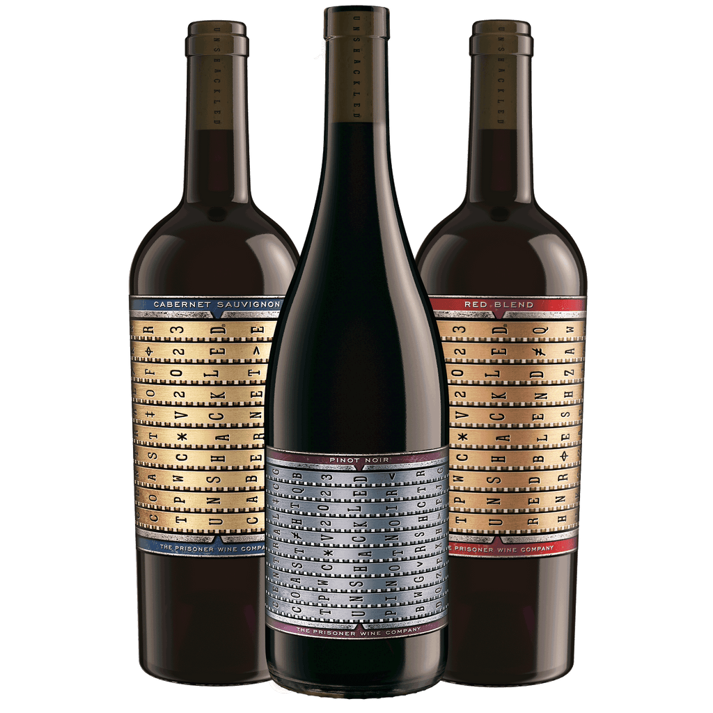 One bottle each of Unshackled Red Blend, Pinot Noir, and Red Blend, with vintage-style labels featuring a gold grid and black text, arranged together on a plain white background.