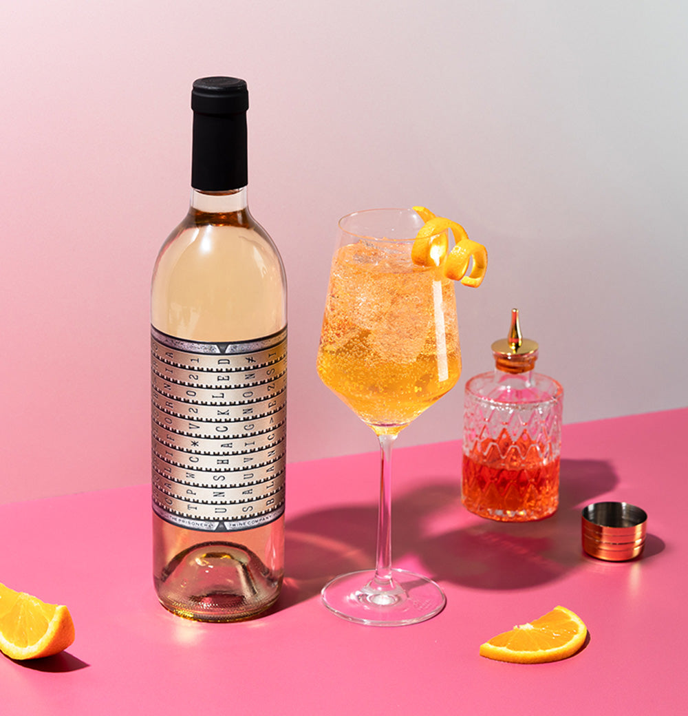 A bottle of Unshackled Sauvignon Blanc on a table next to a cocktail a