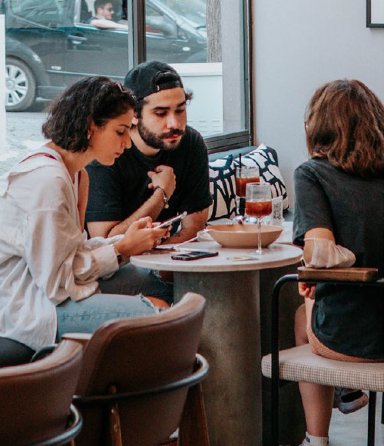 Three people sitting around a table in a casual setting, possibly a cafe or restaurant.