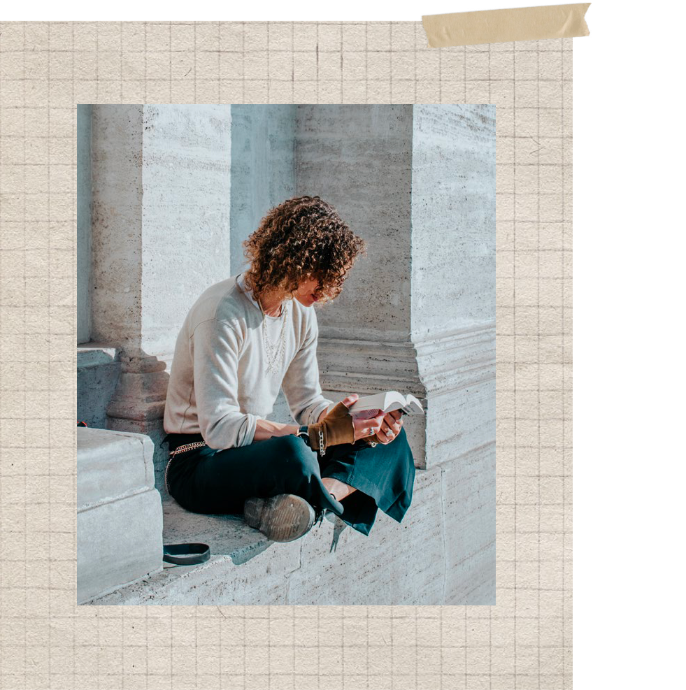 A square art print or poster featuring a photograph of a person with curly hair sitting on stone steps and holding a pink bottle, surrounded by a beige grid border and a tan tape graphic at the top.